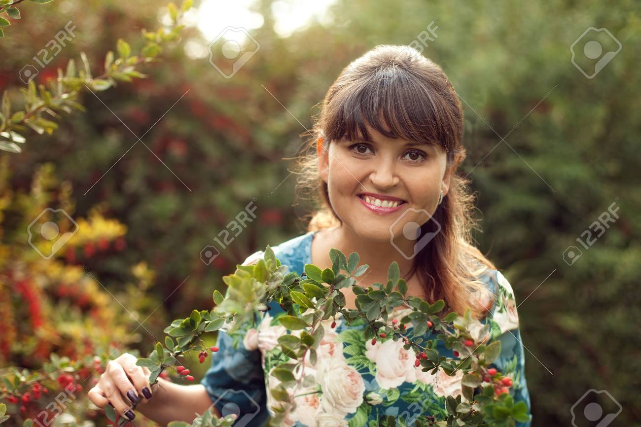 beautiful happy brunette woman in the park on a warm summer day, a girl in a floral dress walks outdoors - 66916837 beautiful happy brunette woman in the park on a warm summer day, a girl in a floral dress walks outdoors - 66916837