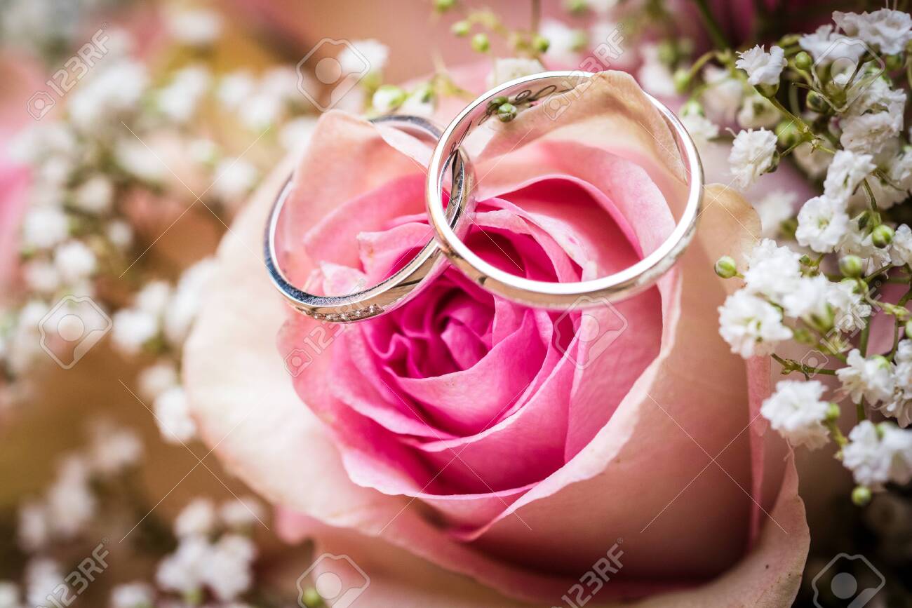 Wedding bouquet with pink roses on wooden table with rings. Wedding rings and beautiful wedding bouquet on natural wooden desk with nature in background. Close up of pink, purple and green flowers - 134415779 Wedding bouquet with pink roses on wooden table with rings. Wedding rings and beautiful wedding bouquet on natural wooden desk with nature in background. Close up of pink, purple and green flowers - 134415779