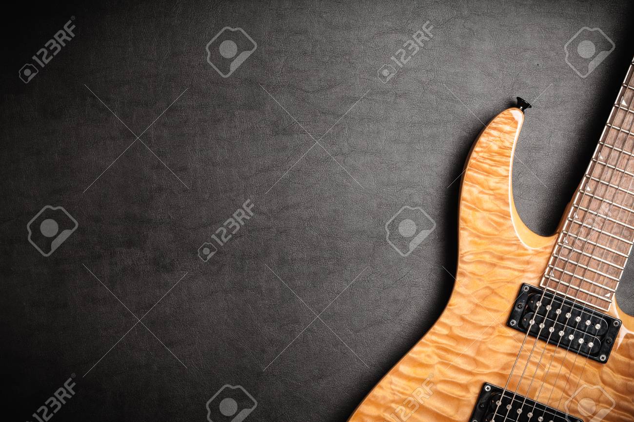 electric guitar with natural wood finish on dark leatherbackground