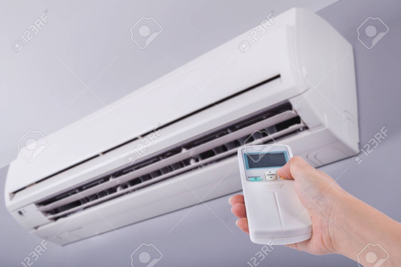 Hand holding remote control directed on the air conditioner - 75000731 Hand holding remote control directed on the air conditioner - 75000731