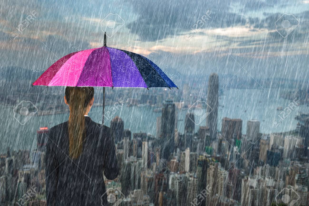 business woman holding multicolored umbrella with falling rain