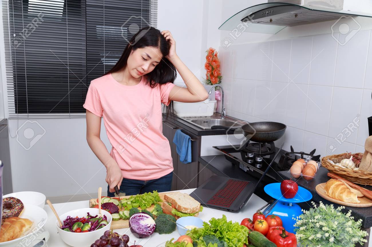 depressed young woman cooking in kitchen room - 98443077 depressed young woman cooking in kitchen room - 98443077