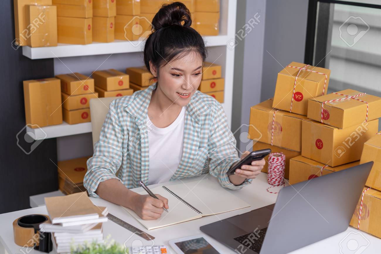young woman entrepreneur checking and writting order with cardboard , SME business online prepare for delivery to customers in home office - 116869343 young woman entrepreneur checking and writting order with cardboard , SME business online prepare for delivery to customers in home office - 116869343
