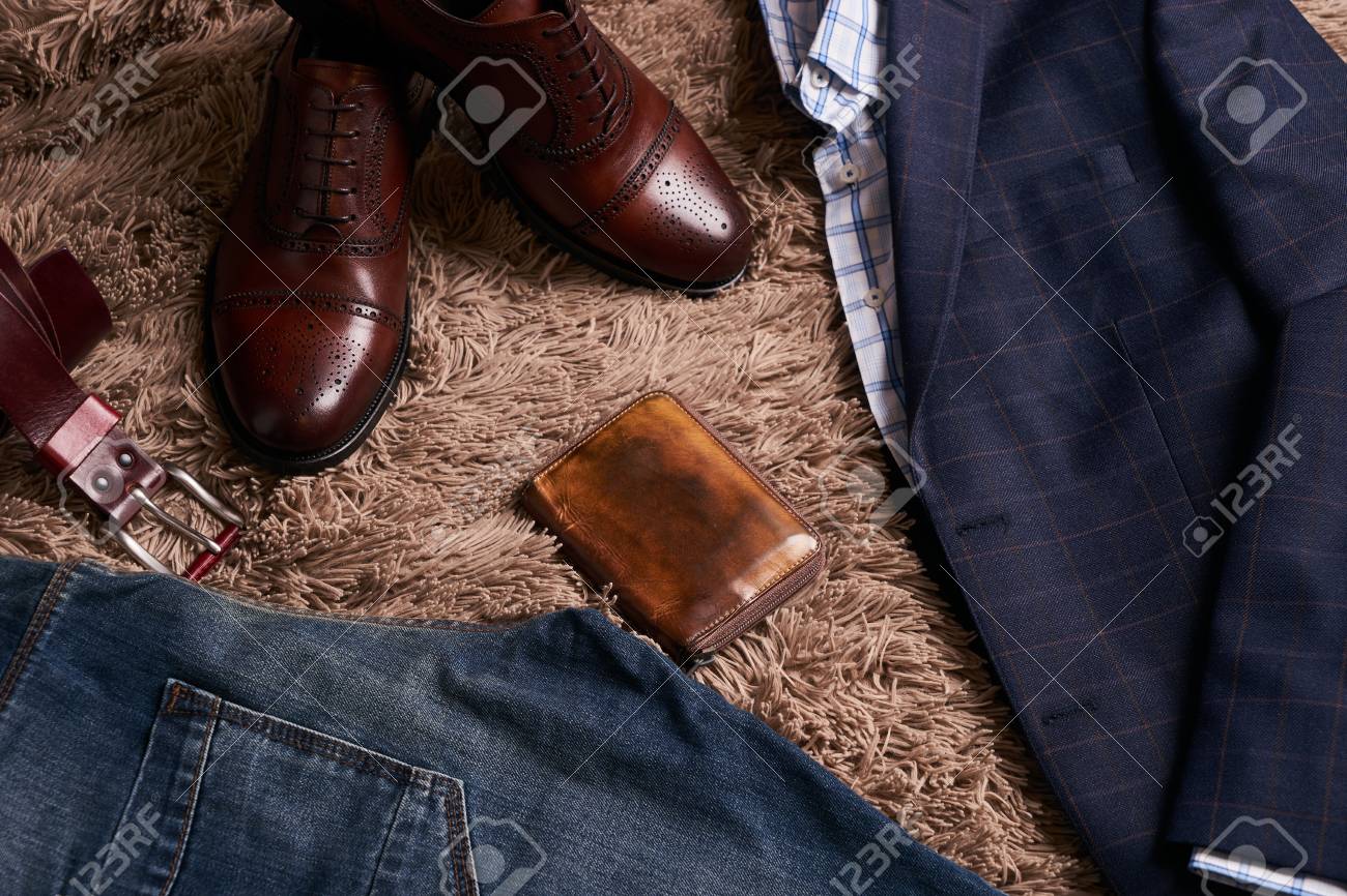 明るいシャツ ジーンズのズボン 茶色の革の靴 柔らかいカーペットの背景にベルトと財布を持つダークスーツジャケットなどの古典的な男性の服のセット の写真素材 画像素材 Image
