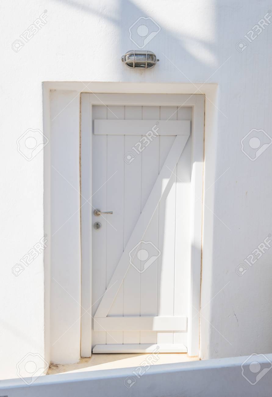 Front view of white wooden door in a whitewashed wall. Traditional.. Front view of white wooden door in a whitewashed wall. Traditional..