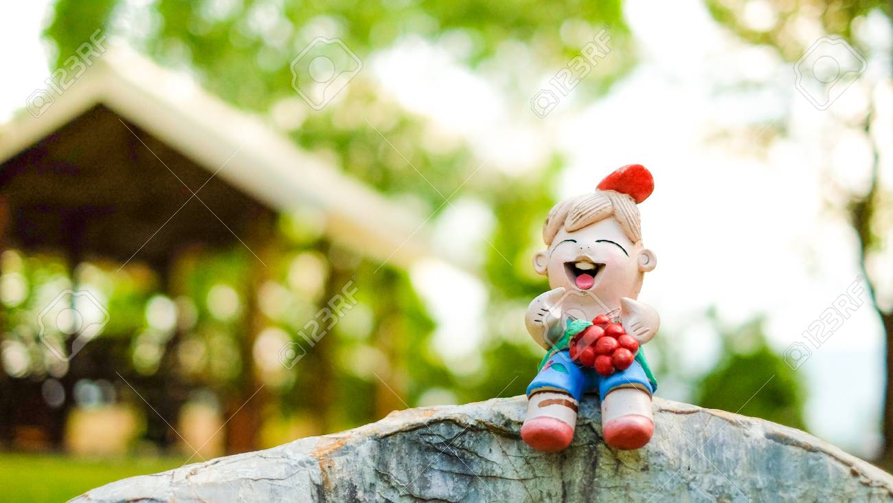 石膏人形中国の女の子は 背景のボケ味と岩の上に座っている市場で購入することができますグレープ フルーツと笑顔します の写真素材 画像素材 Image