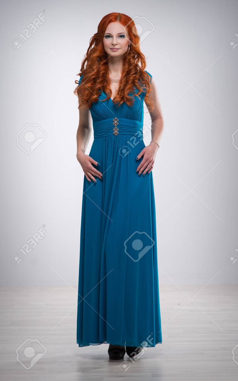 Schöne Junge Frau Mit Roten Haaren In Einem Schönen Blauen Kleid,  Rothaarige Mädchen Mit Lockigen Haaren Stehen Auf Grauem Hintergrund,  Lizenzfreie Fotos, Bilder und Stock Fotografie. Image 69986552.
