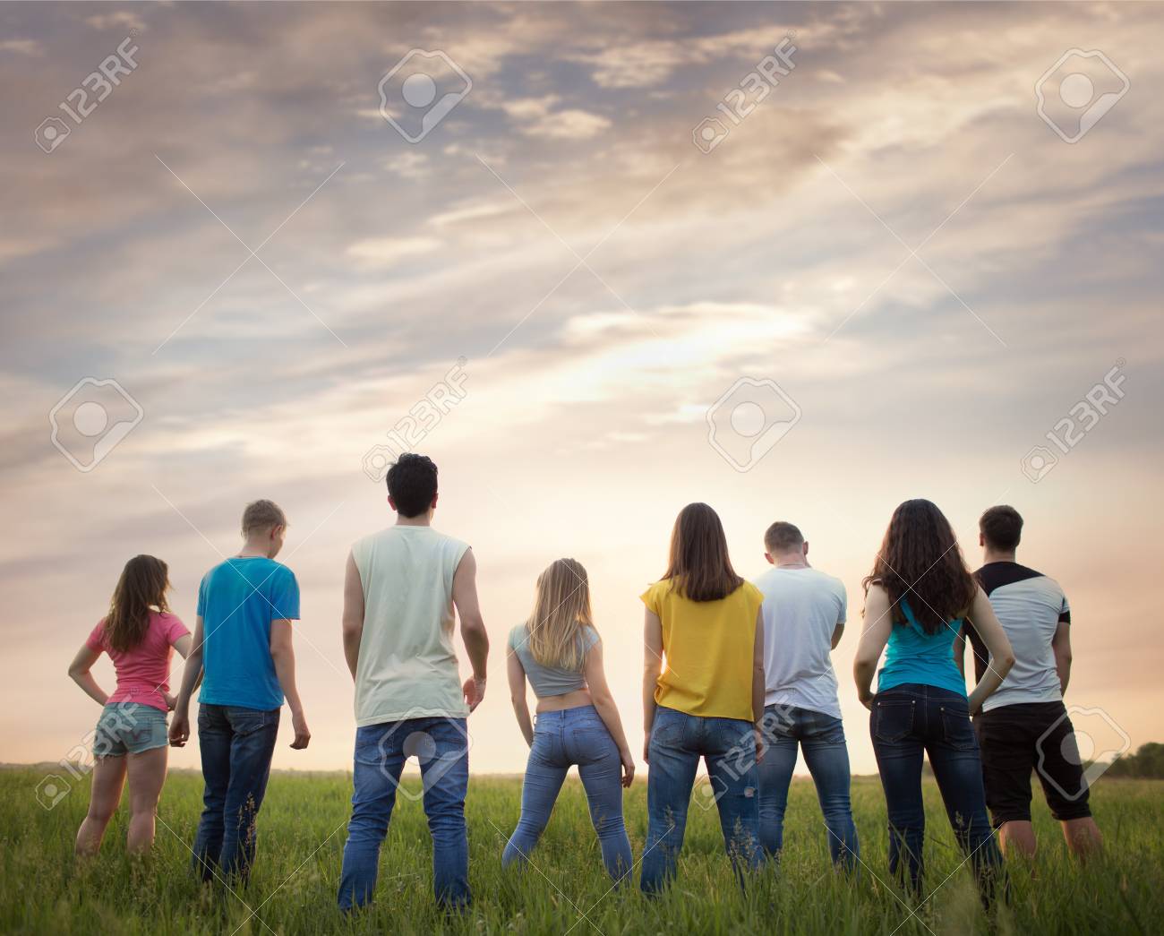 Group Young People, Outdoors. People Stand With Their Backs Against The  Beautiful Sunset Sky Stock Photo, Picture and Royalty Free Image. Image  102022995.