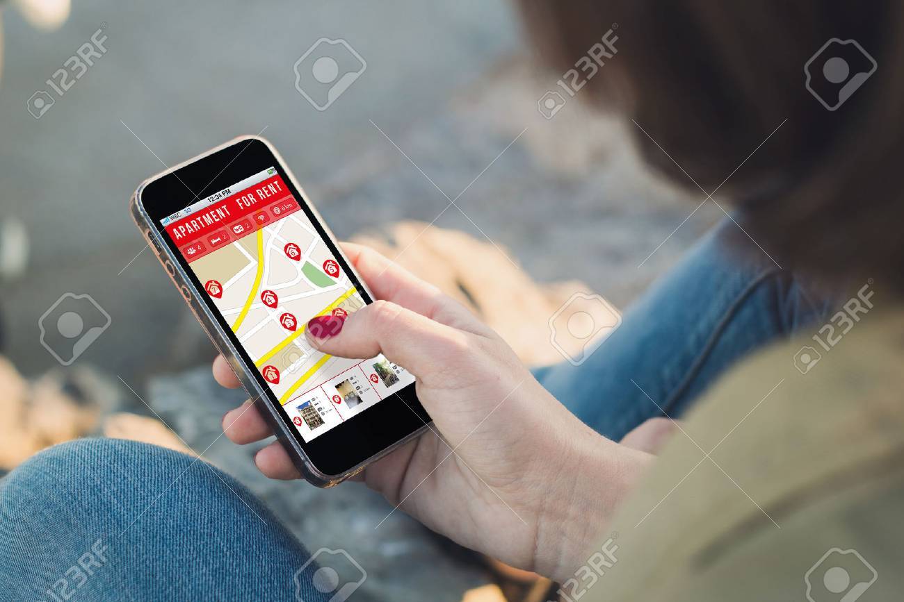 woman holding a smartphone with apartment search on screen. all woman holding a smartphone with apartment search on screen. all