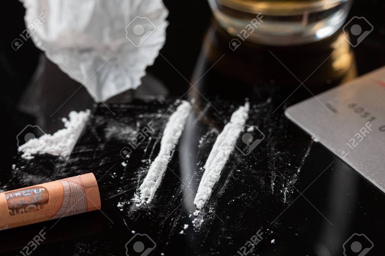 Cocaine lines prepared on a table and a rolled banknote ready to be sniffed - 150431242 Cocaine lines prepared on a table and a rolled banknote ready to be sniffed - 150431242