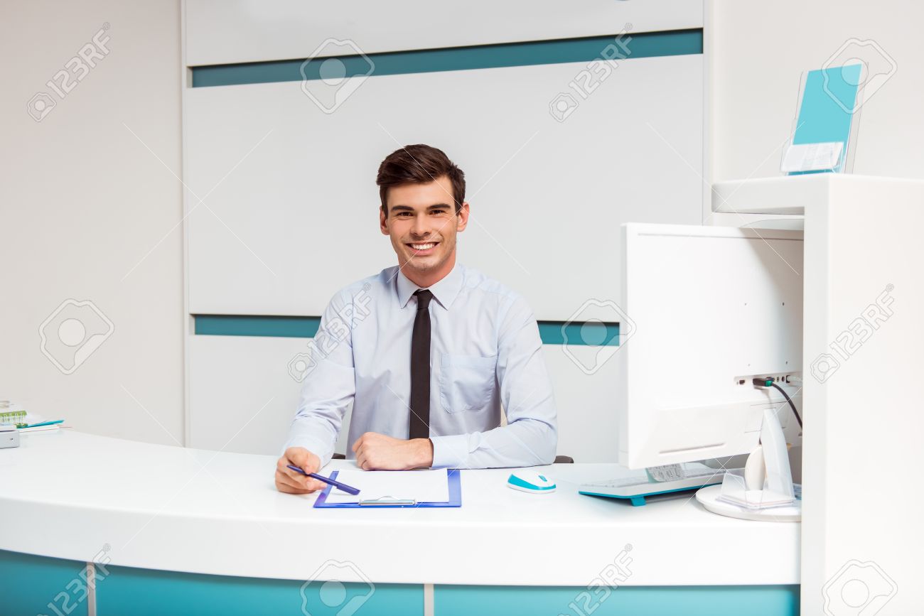 Réceptionniste De Bureau : Portrait d un jeune homme souriant avec réceptionniste au