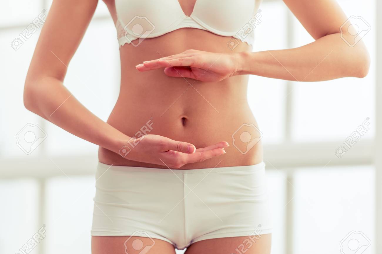 彼女のお腹の前に手を維持する白い下着で美しいスリムな女の子の画像をトリミング の写真素材 画像素材 Image