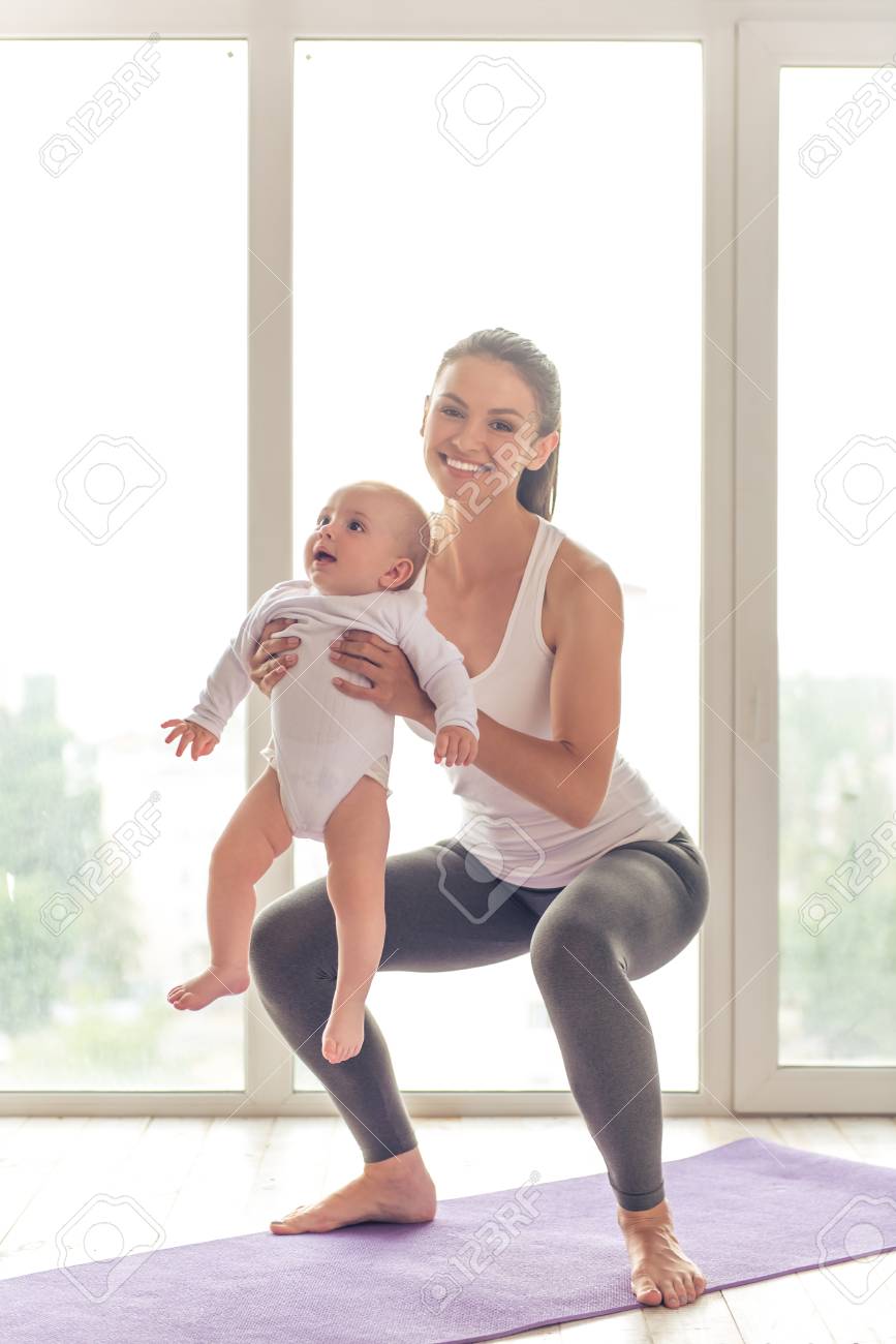 Belle Jeune Maman Dans Les Vetements De Sport Est Souriant Tout En Faisant Du Yoga Avec Son Charmant Petit Bebe Sur Un Tapis Contre La Fenetre Banque D Images Et Photos Libres De