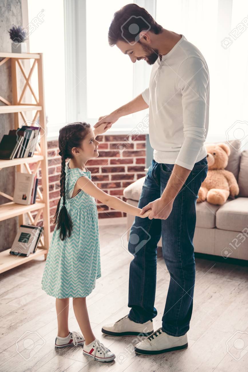 Cute little girl and her handsome father are smiling while dancing together at home - 70041162 Cute little girl and her handsome father are smiling while dancing together at home - 70041162