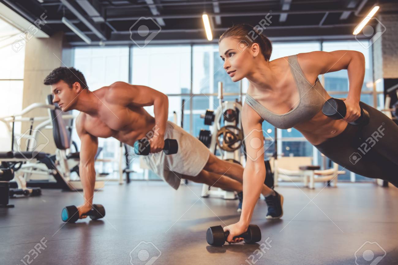 Attractive young sports people are working out with dumbbells in gym - 70653995 Attractive young sports people are working out with dumbbells in gym - 70653995