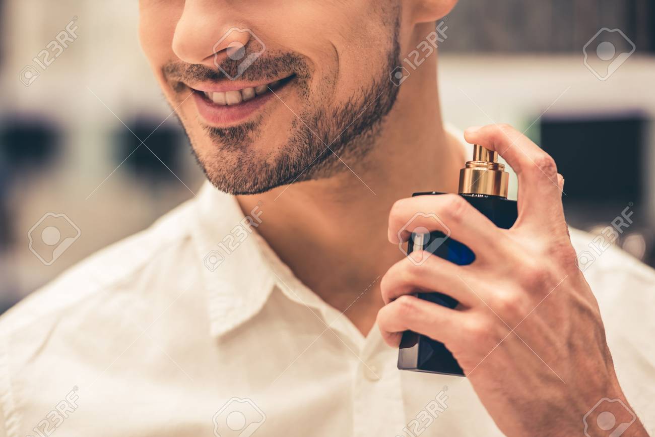 Handsome guy is choosing perfumes and smiling while doing shopping in the mall - 74025283 Handsome guy is choosing perfumes and smiling while doing shopping in the mall - 74025283