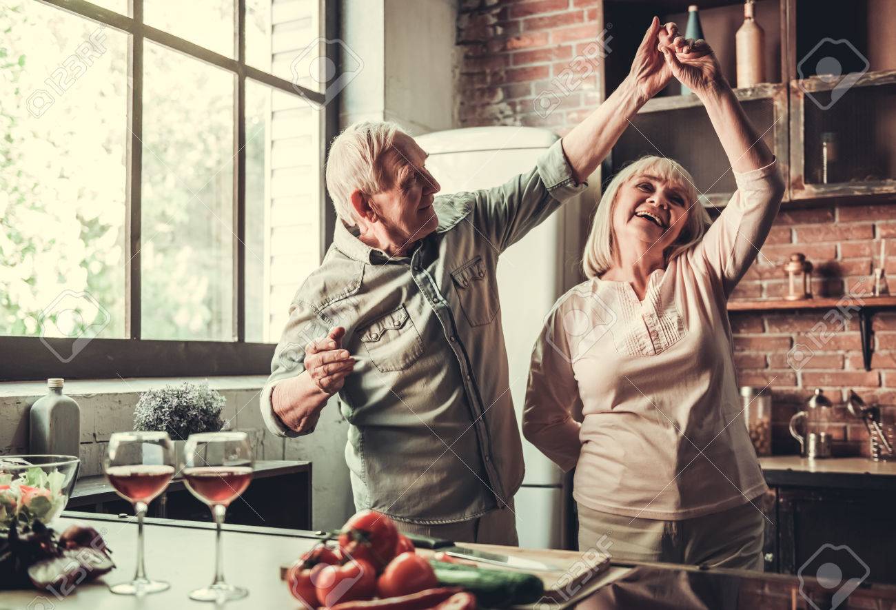 Beautiful senior couple is dancing and smiling while cooking together in kitchen - 79737459 Beautiful senior couple is dancing and smiling while cooking together in kitchen - 79737459