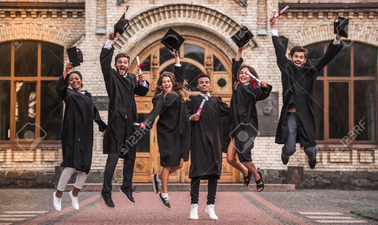 Successful graduates in academic dresses are holding diplomas, looking at camera and smiling while jumping for the photo outdoors - 88355323 Successful graduates in academic dresses are holding diplomas, looking at camera and smiling while jumping for the photo outdoors - 88355323