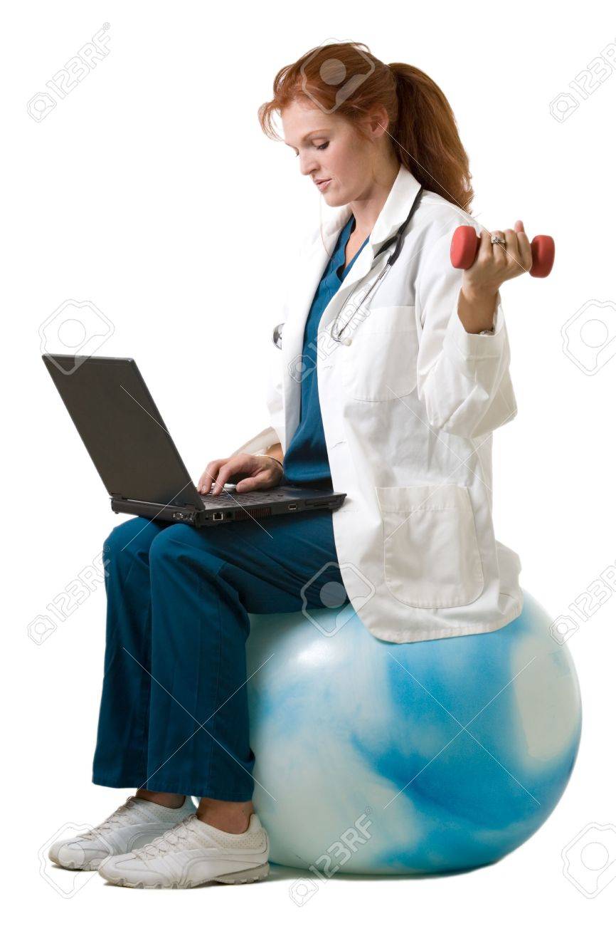 魅力的な赤い髪女医運動ボール手の重量を使用して ラップトップ コンピューターを入力して上に座っている白衣を着ています の写真素材 画像素材 Image