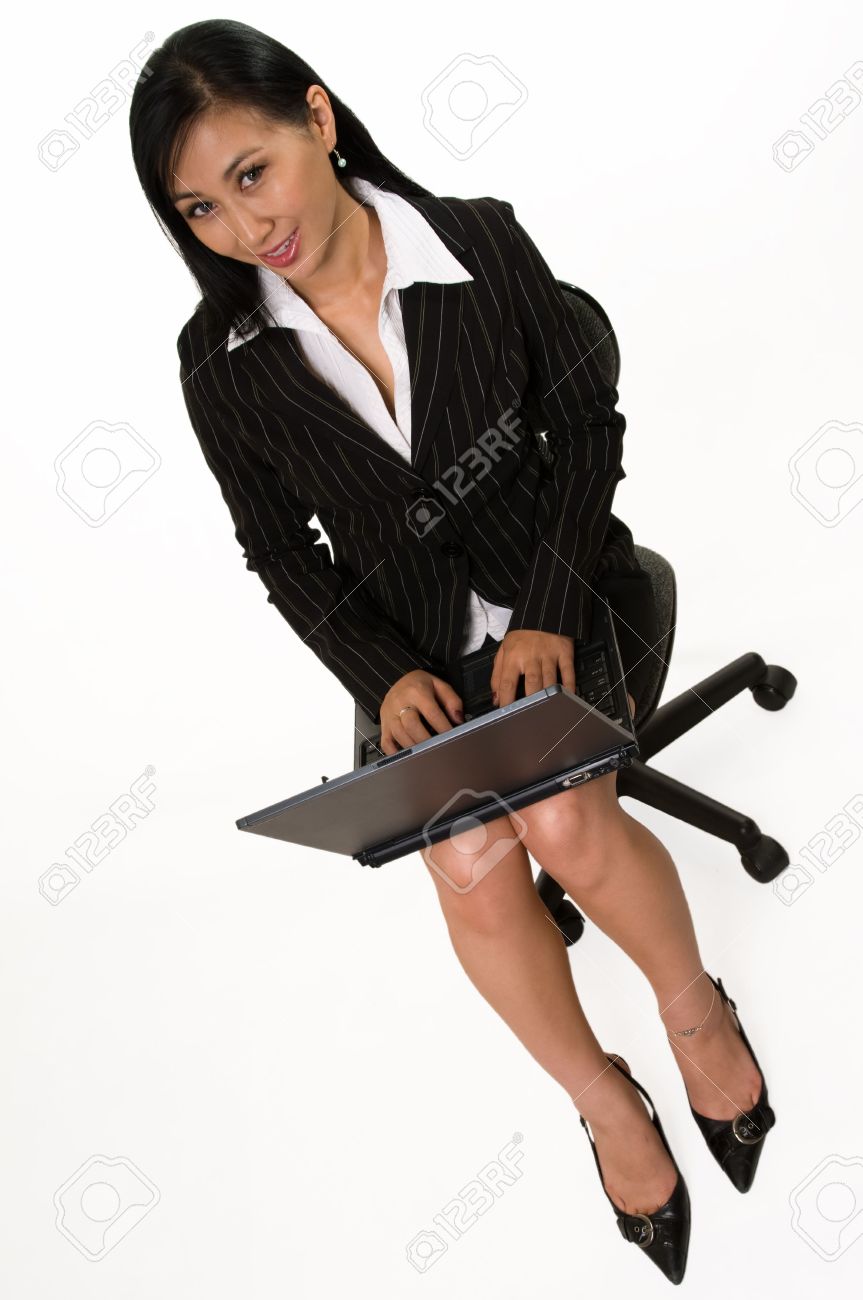 Full Body Of An Attractive Asian Woman Wearing Black Business Skirt Suit Sitting On Chair And Holding Laptop On Legs Over White Full Body Of An Attractive Asian Woman Wearing Black Business Skirt Suit Sitting On Chair And Holding Laptop On Legs Over White