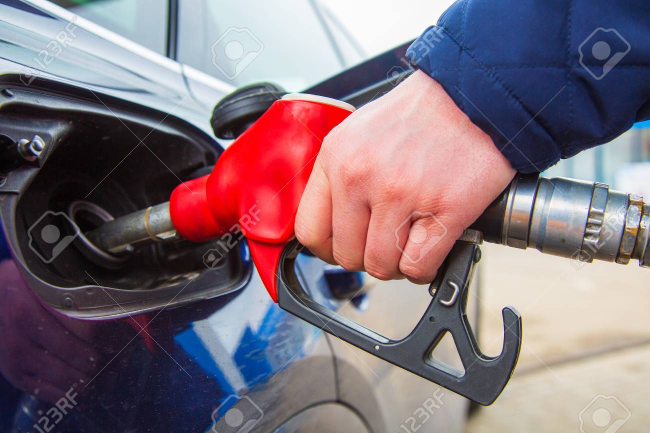 Fuelling gun inserted into the tank of blue car - 101559458 Fuelling gun inserted into the tank of blue car - 101559458