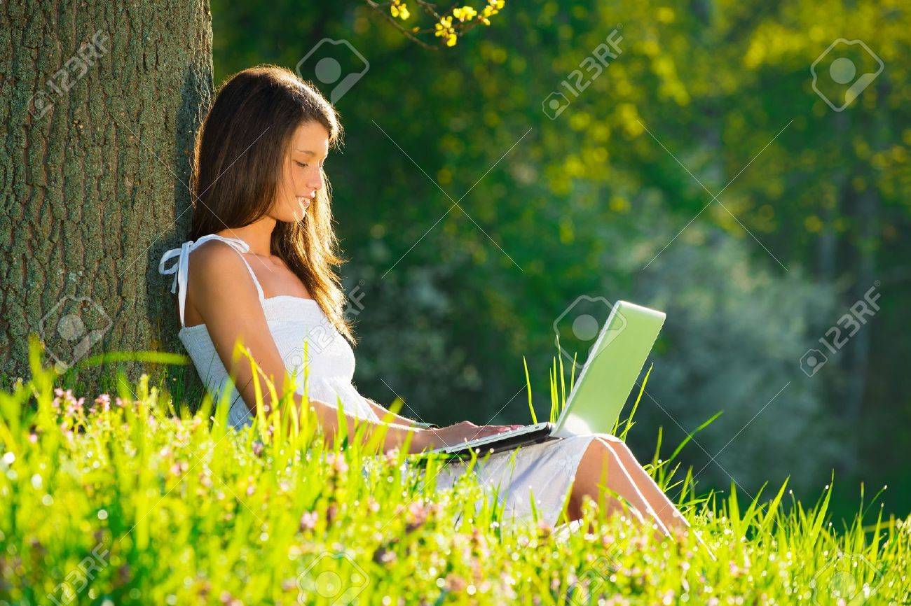 Beautiful young woman relaxing on grass with laptop - 19428711 Beautiful young woman relaxing on grass with laptop - 19428711