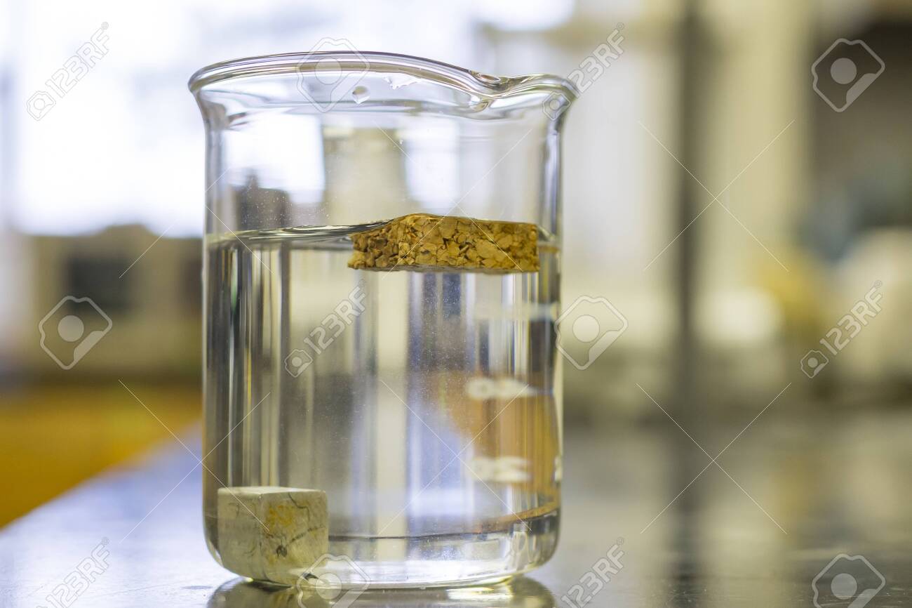 Density Of 2 Different Materials In A Beaker. One Object Floating