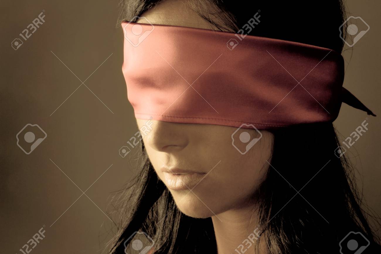 Close-up of woman in soft silk blindfold, lips parted in dreamy surrender, warm shadows across face
