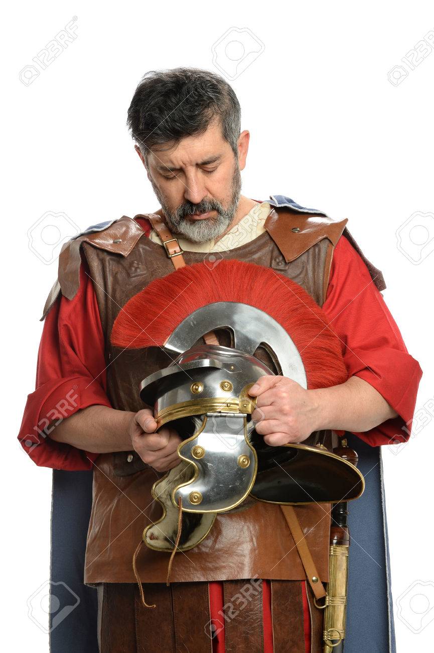 portrait of roman soldier praying while holding helmet stock photo