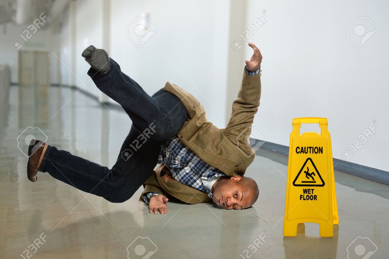 African American businessman falling on wet floor in office - 47035236 African American businessman falling on wet floor in office - 47035236