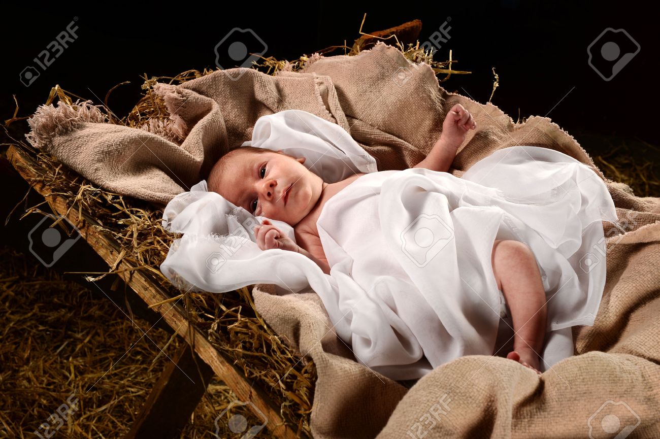 Baby Jesus when born on a manger wrapped in swaddling clothes over dark background - 63773770 Baby Jesus when born on a manger wrapped in swaddling clothes over dark background - 63773770