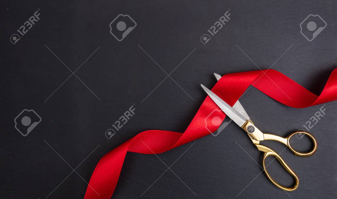 Grand opening. Top view of gold scissors cutting red silk ribbon against black background, copy space - 114522505 Grand opening. Top view of gold scissors cutting red silk ribbon against black background, copy space - 114522505