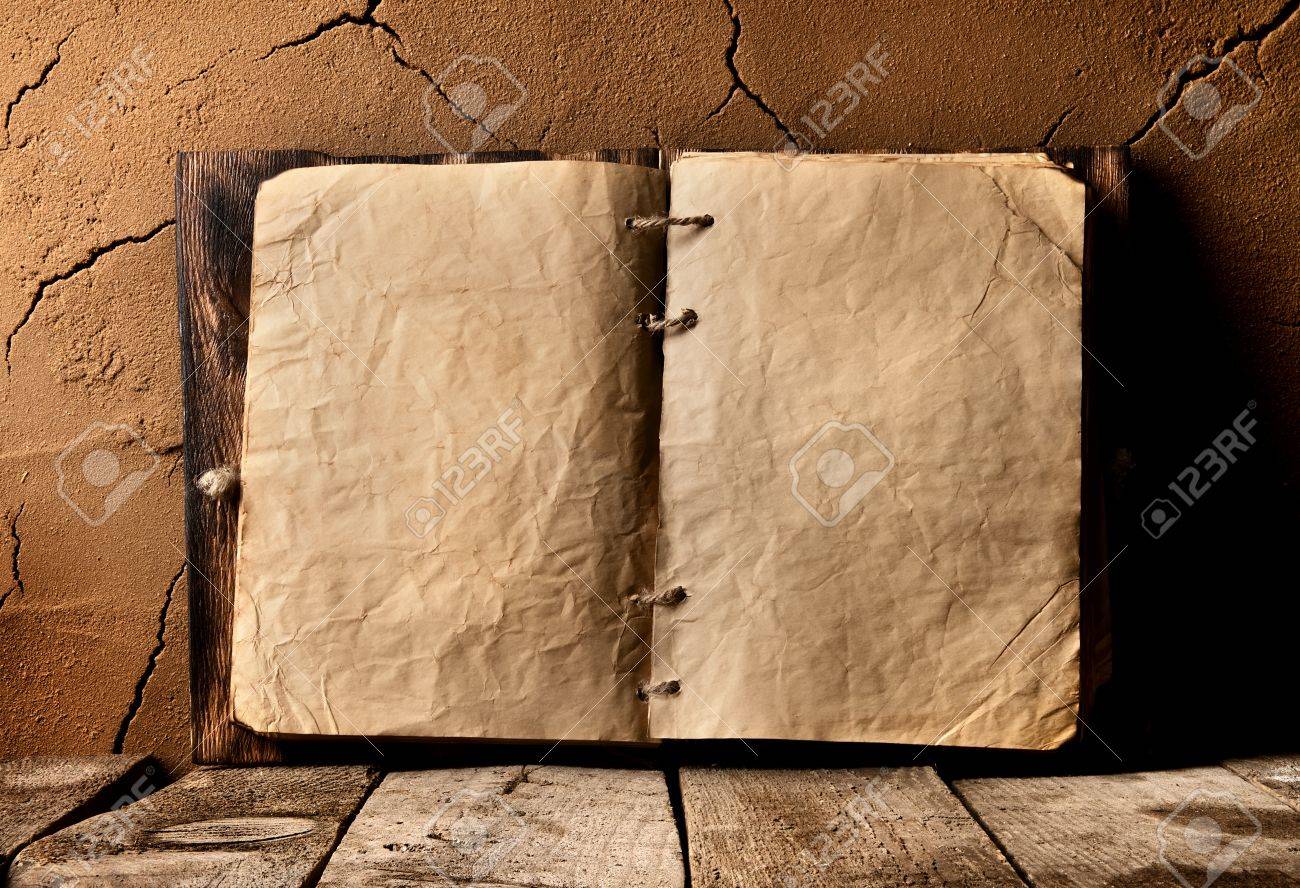 Opened old book on table near clay wall - 54300916 Opened old book on table near clay wall - 54300916