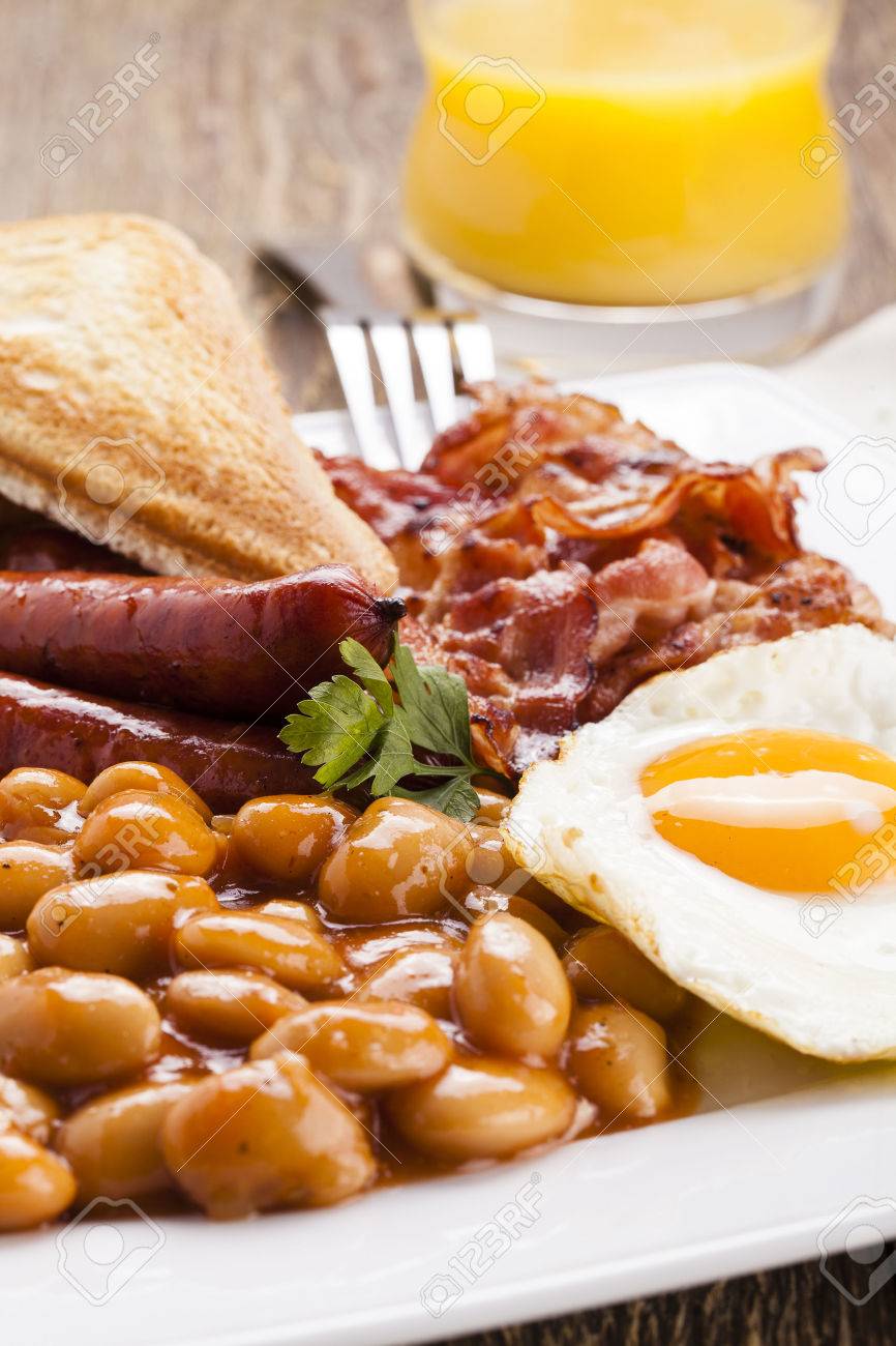 イングリッシュ ブレックファスト ベーコン ソーセージ 目玉焼き 焼きたての豆 紅茶またはオレンジ ジュース の写真素材 画像素材 Image