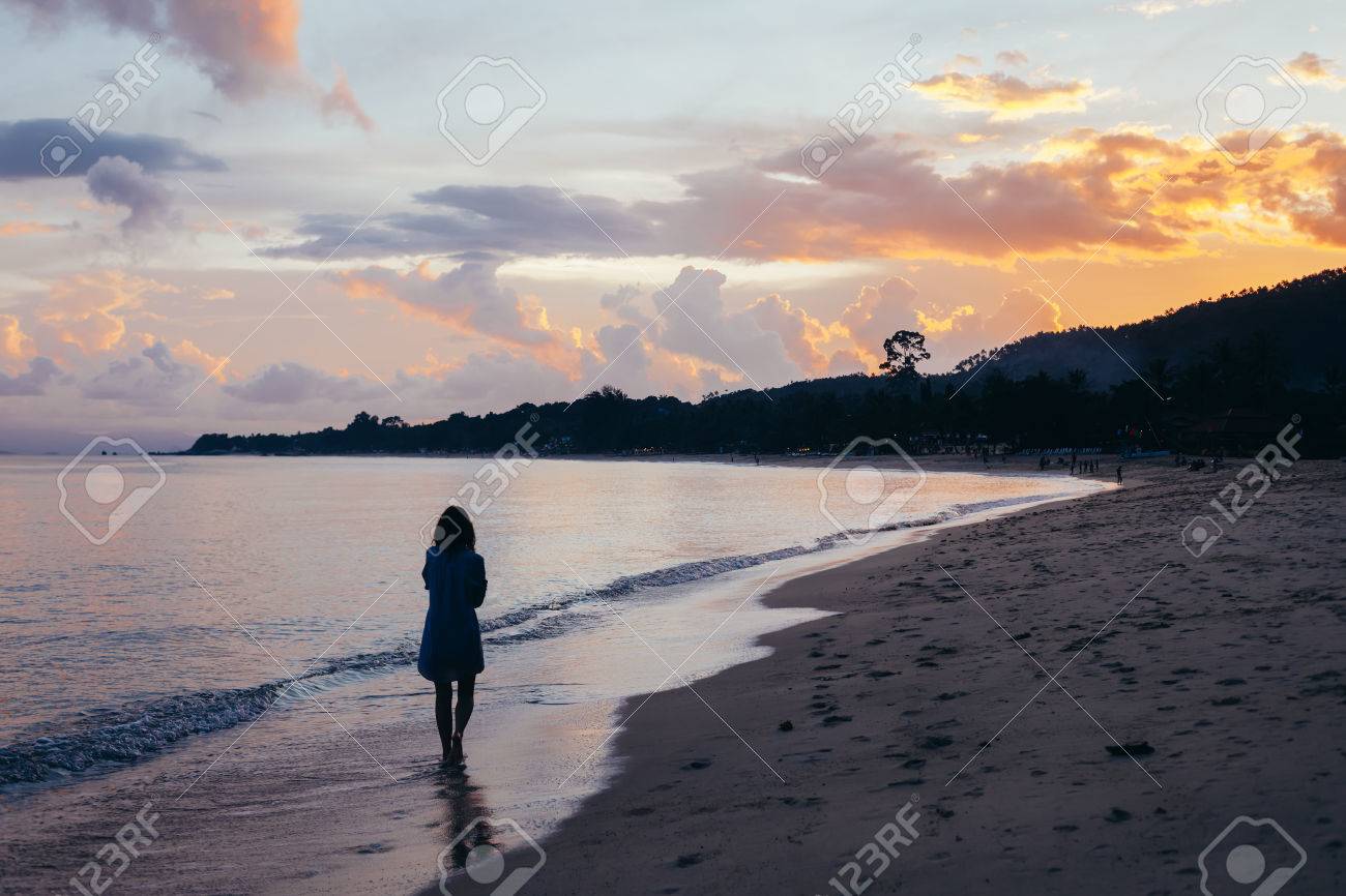 夕日の砂浜の上を歩いて孤独な女性の背面図 の写真素材 画像素材 Image