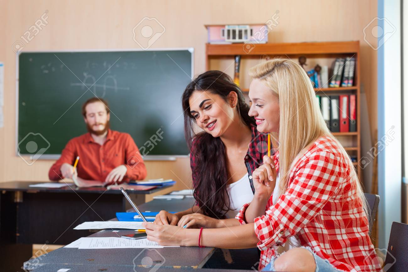 タブレット コンピューター高校を使用して 2 つの美しい若い女の子 学生の笑顔を着用チェック シャツ座るデスク大学教室教授で の写真素材 画像素材 Image 62492944