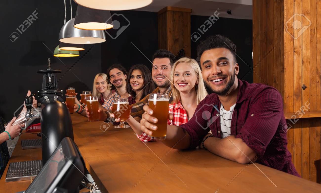 Young People Group In Bar, Hold Beer Glasses, Friends Sitting At Wooden  Counter Pub, Friends Toast, Communication Party Celebration Stock Photo,  Picture and Royalty Free Image. Image 62990509.