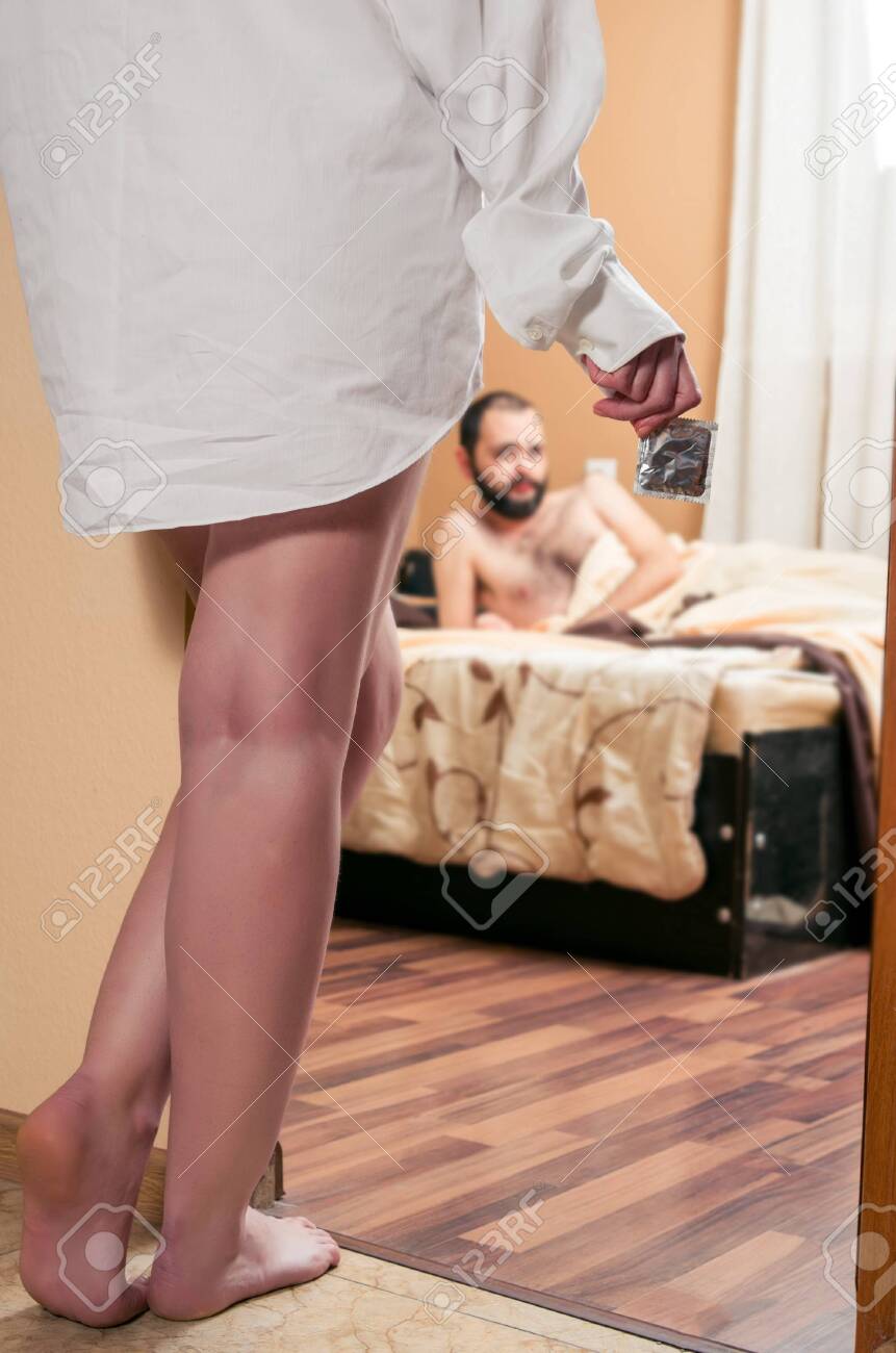 ベッドで待っている男性がコンドームを持って寝室に入る女性の写真素材・画像素材 Image 119331614