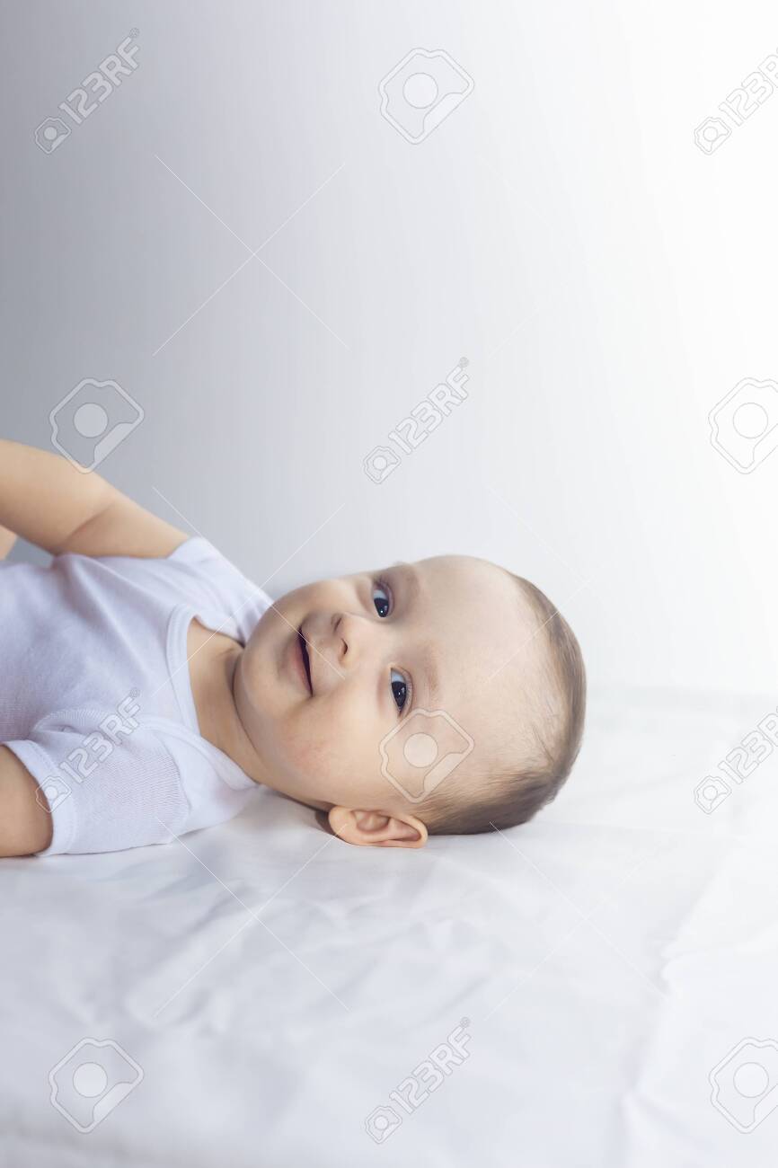 6-month baby having fun in white bedding. Cute baby lying on bed. Family, new life, childhood conception. - 124612940 6-month baby having fun in white bedding. Cute baby lying on bed. Family, new life, childhood conception. - 124612940