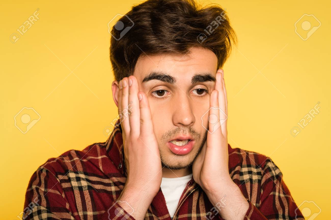 Dumbfounded And Taken Aback Man Clutching His Head And Panicking. Feelings  Of Regret Remorse And Dismay. Portrait Of A Young Handsome Brunet Guy On  Yellow Background. Emotion Facial Expression. Фотография, картинки,  изображения