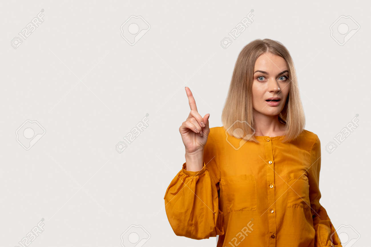 Warning Gesture. Disturbed Woman. Shock Discovery. Aha Moment. Portrait Of  Worried Confused Lady In Yellow Blouse Pointing Up Isolated On Light  Neutral Copy Space Background. Stock Photo, Picture and Royalty Free Image.