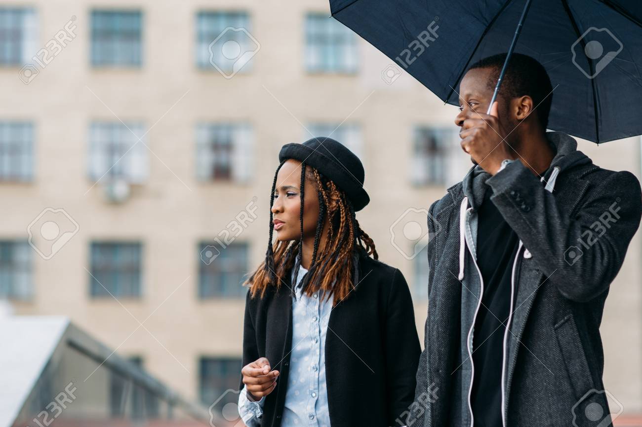 思慮深いファッションの歩行者 雨の気分 若い黒人夫婦の傘 幸せなアフリカ系アメリカ人 遠近の概念 の写真素材 画像素材 Image