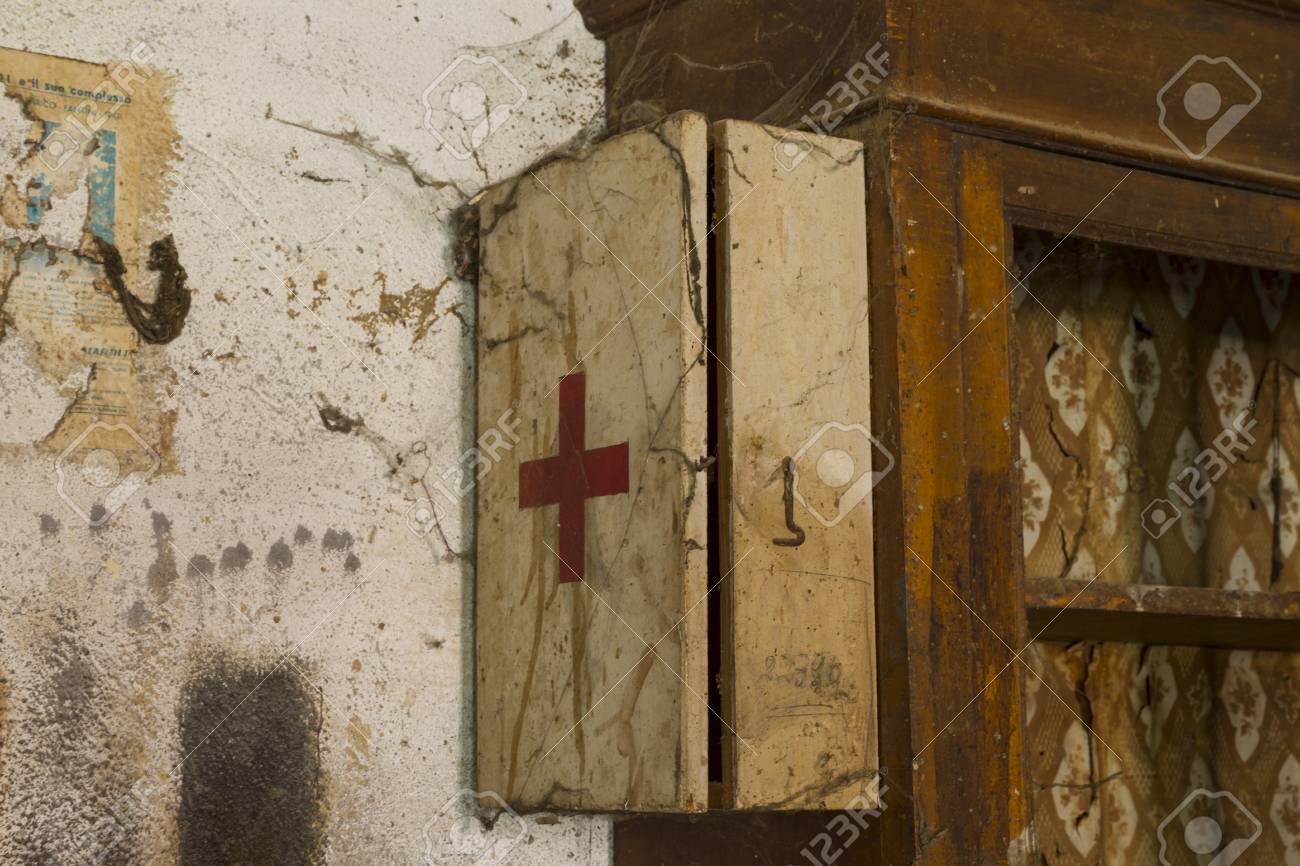 an old first aid kit on a dirty and rusty wall covered by cobwebs