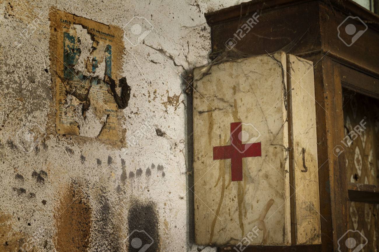 an old first aid kit on a dirty and rusty wall covered by cobwebs