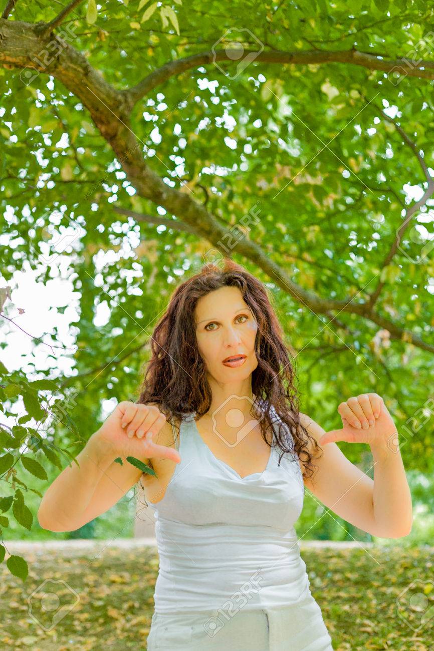 Unhappy Busty Classy Mature Woman Giving Thumbs Down Gesture Looking With  Negative Expression At The Camera Against Green Garden Background With Copy  Space Stock Photo, Picture and Royalty Free Image. Image 59877155.