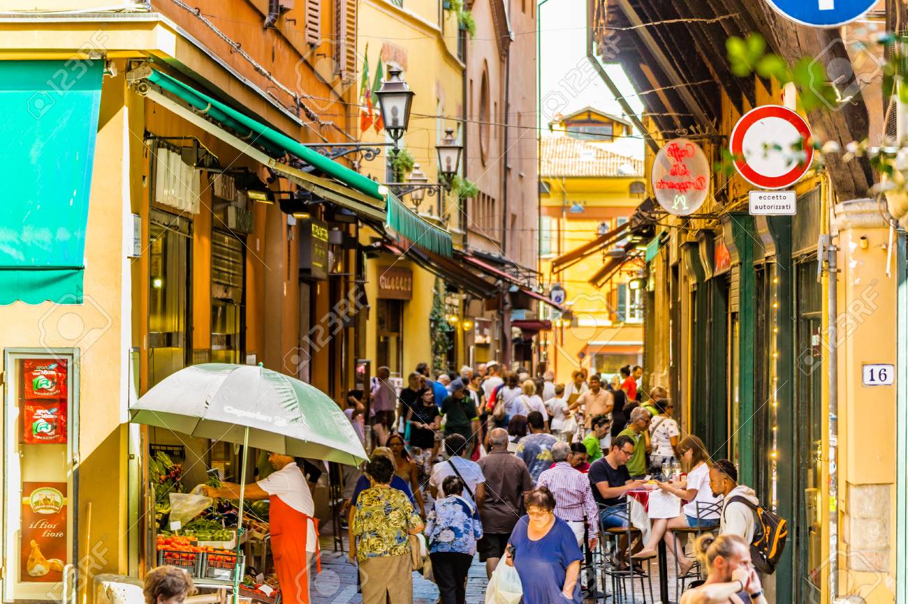 Bolonia, Italia - 27 De Agosto De 2016: Turistas Y Lugareños Van De Compras En El Mercado Medieval. La Vocación Comercial De Esta Zona Como Quadrilatero, Es Decir, Cuadrilátero,