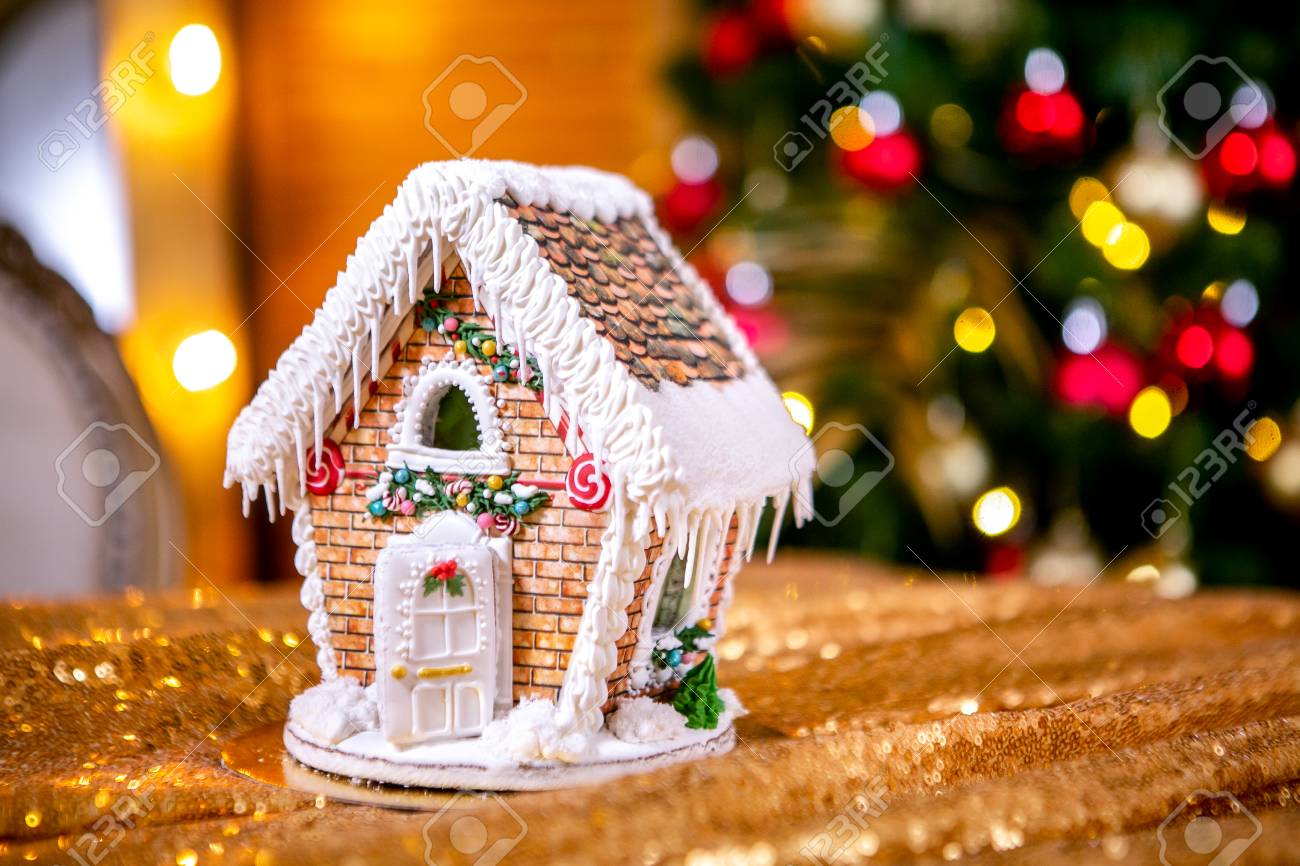 Gingerbread house in front of defocused lights of Christmas decorated..