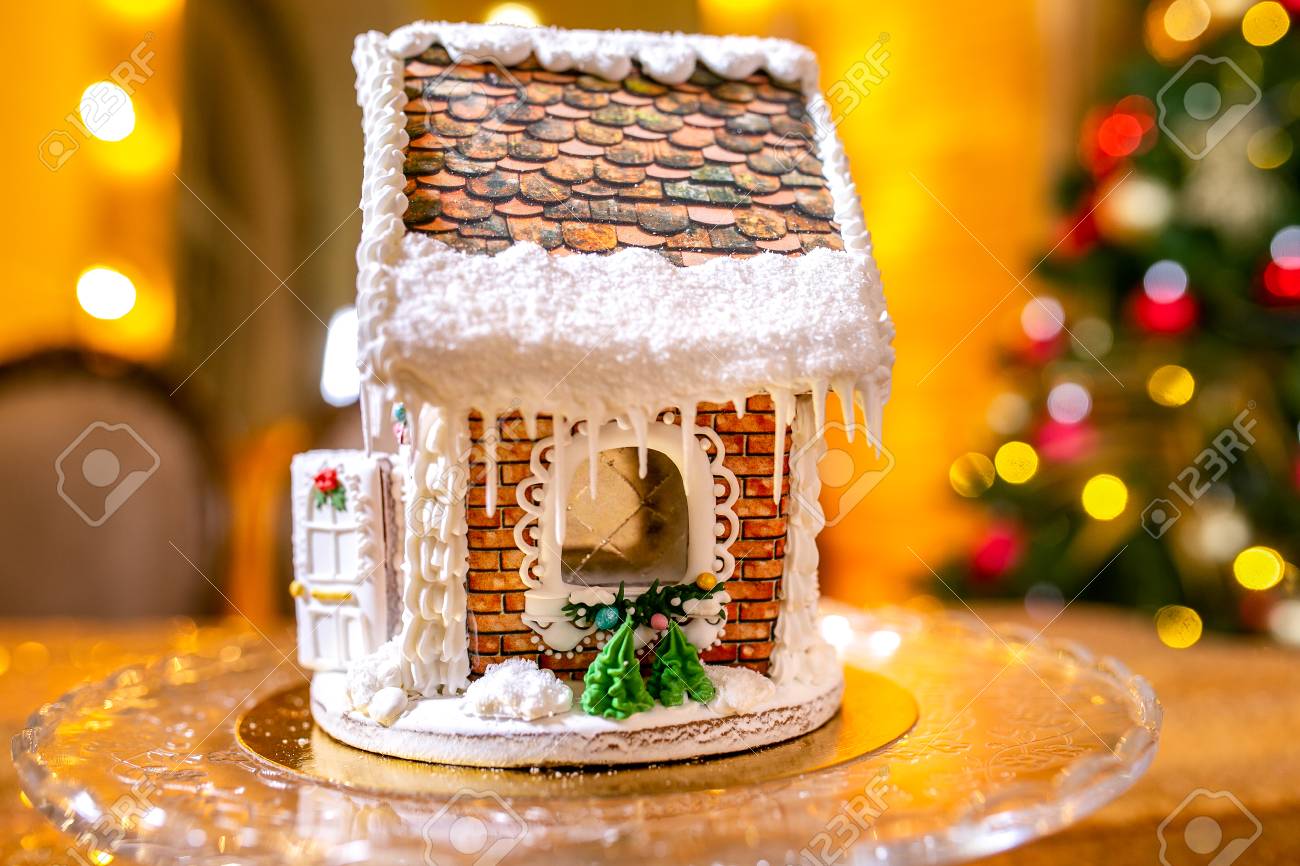 Gingerbread house in front of defocused lights of Christmas decorated..