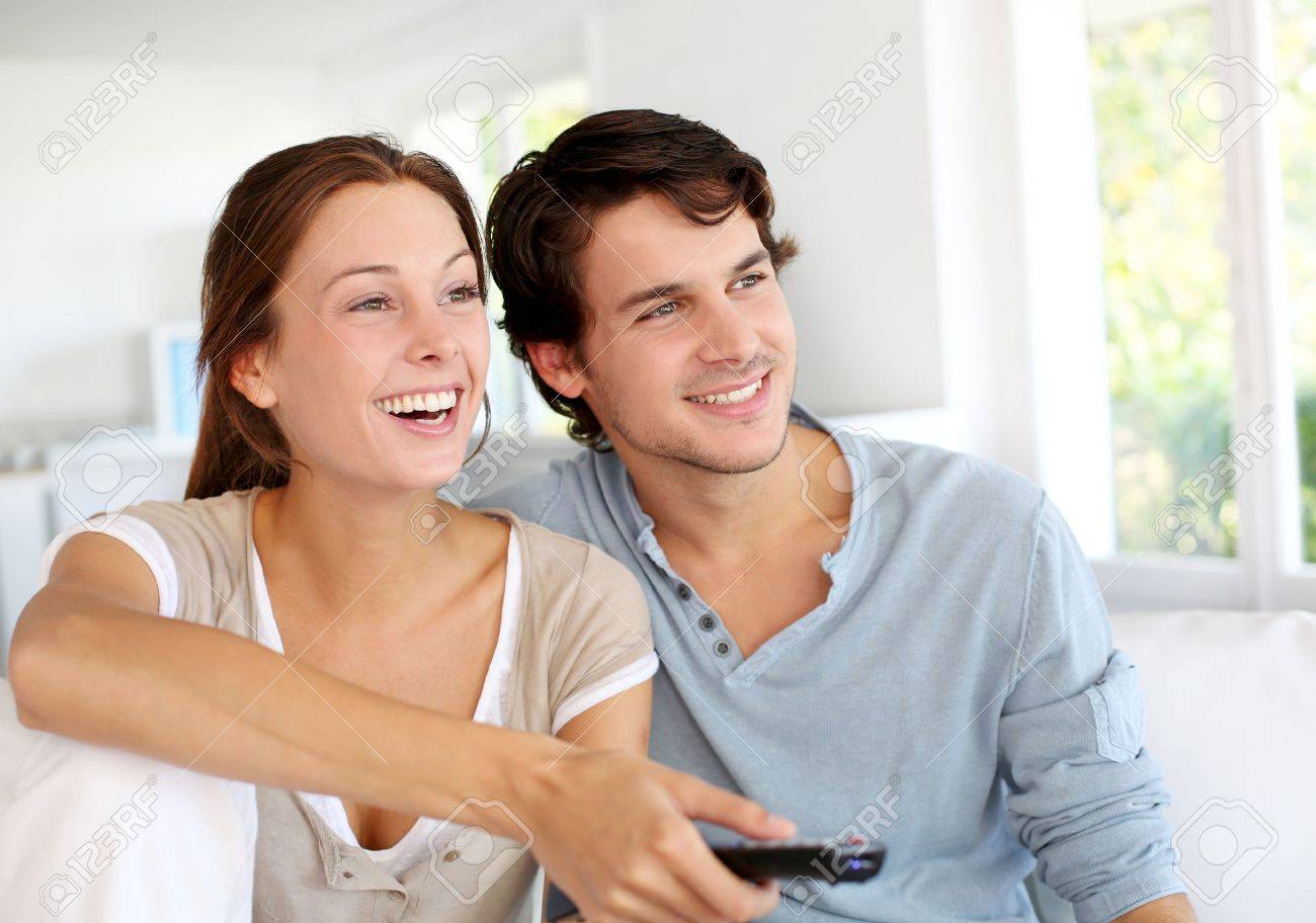 Couple sitting in sofa with remote control in hands - 15279248 Couple sitting in sofa with remote control in hands - 15279248