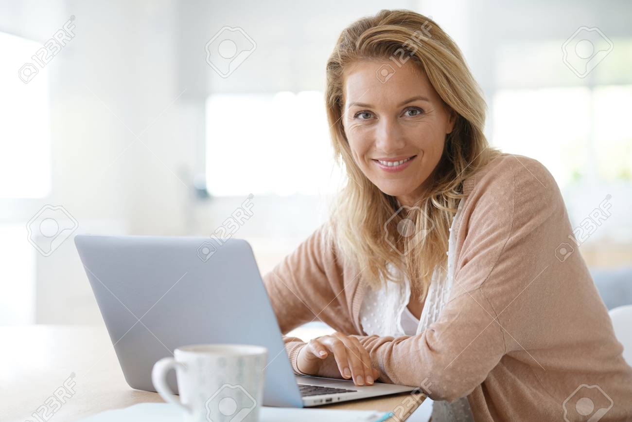 Attractive blond woman working on laptop computer at home - 86417220 Attractive blond woman working on laptop computer at home - 86417220